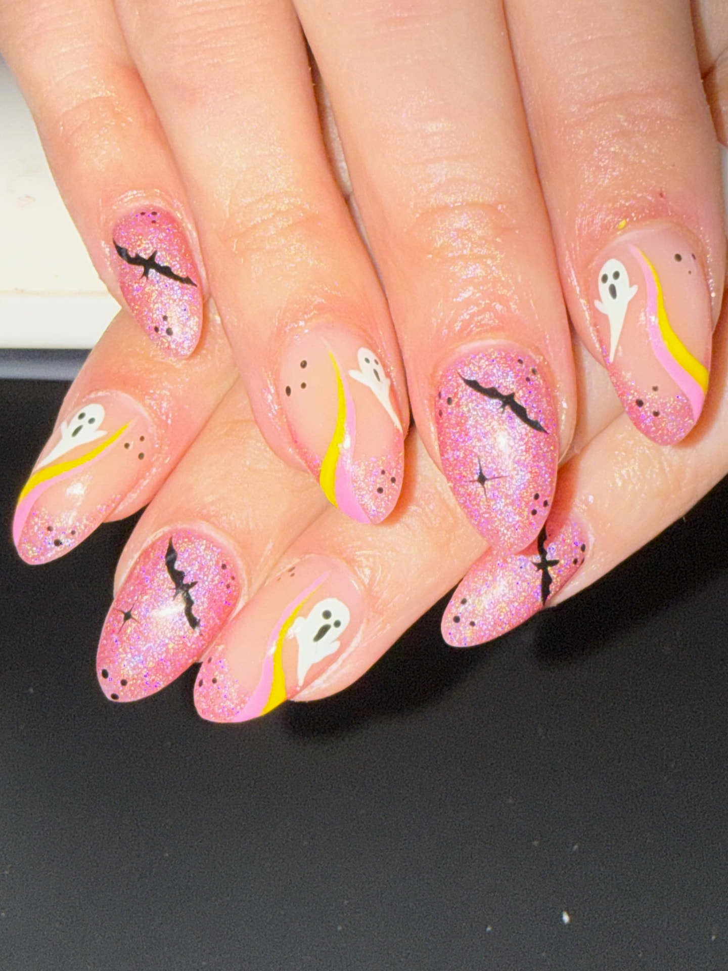 Pink glitter almond nails with white ghosts and black bat silhouettes