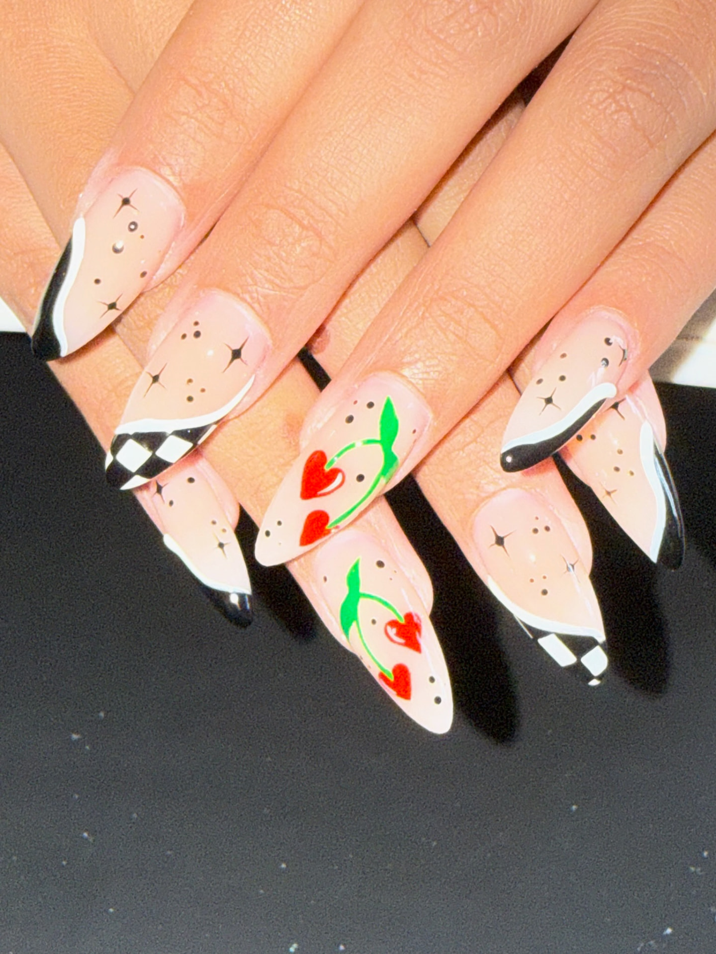 Nude almond nails with cherries, checkerboard tips and black accents