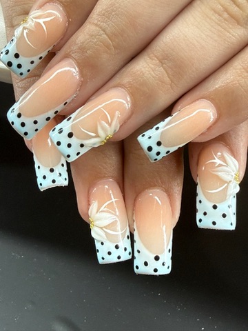 Pale blue French-tip nails with black polka dots and raised white flowers